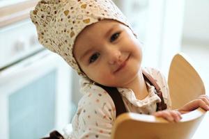 retrato de una linda niñita casera en una cocina blanca. foto