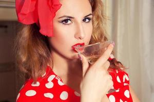 mujer en estilo pinup bebe martini del vaso foto