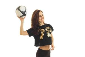 una joven atlética sonríe y levanta una pelota de fútbol en la mano foto