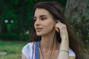 close up portrait of young brunette girl listening music with headphones photo