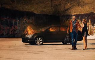 glamorous couple leaves from burning car photo