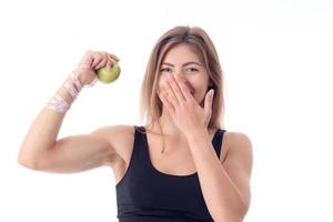 hermosa chica se para directamente y muestra una manzana en una mano y sus bíceps foto