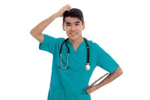 portrait of young nice brunette man doctor in blue uniform with stethoscope looking at the camera and smiling isolated on white background photo