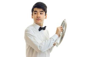 a young waiter in a white shirt looks to the side and side tray for dishware photo