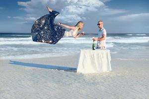 Elegance man in sunglasses and young flying blonde girl on the beach photo