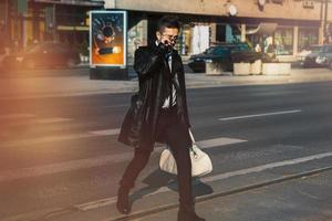 hombre con abrigo de cuero y gafas de sol cruzando la calle foto