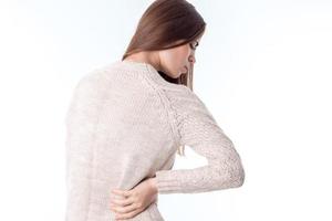 girl in  sweater stands with his back to the camera keeps  hand on the side of feeling pain is isolated   white background photo