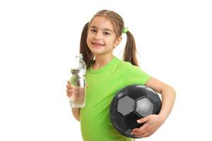 little girl with ball in hands drinks water photo