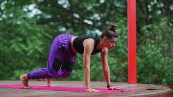 une femme exécute des poses de yoga et s'étire sur une scène extérieure video