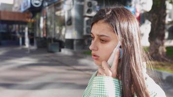 Woman talks on phone on sunny sidewalk video