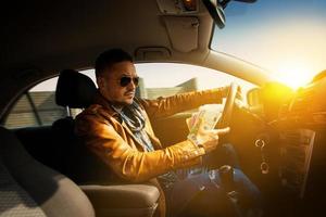 retrato de un hombre concentrado conduciendo un coche con un montón de maney eur en la mano foto