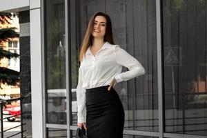 mujer de negocios feliz en uniforme blanco y negro sonríe al aire libre foto