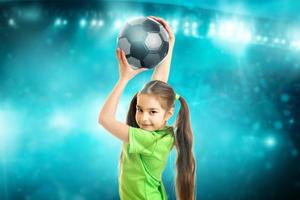 Portrait of a little girl smiles on camera with soccer ball in her hands photo