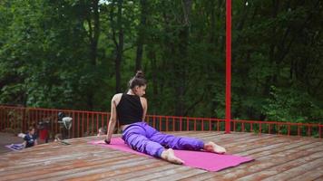 Woman performs yoga poses and stretches on outdoor stage video