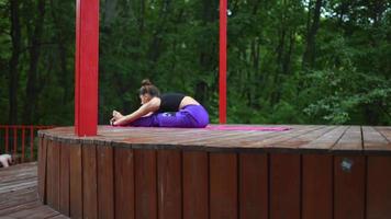 mujer realiza posturas de yoga y se estira en el escenario al aire libre video