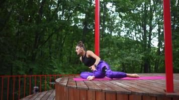 mujer realiza posturas de yoga y se estira en el escenario al aire libre video