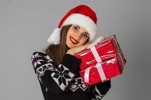 mujer en suéter cálido y sombrero de santa con regalo rojo foto