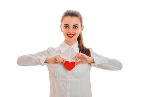 beautiful young girl vbeloj shirt and red lipstick on lips holding a card in the shape of a heart and smiling photo