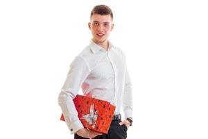 young man in a white shirt with a large red gift smiles at the camera photo