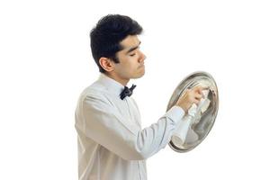 amazing young waiter in a white shirt stands sideways and rub food tray towel photo