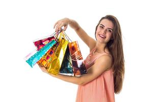 la joven disfruta y sostiene en su mano unas hermosas bolsas de colores aisladas de fondo blanco foto