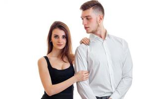 young beautiful girl in black shirt looks straight and holds over the shoulder of the guy in the white shirt photo