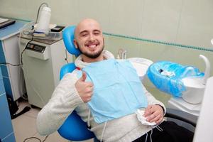 hombre guapo con una sonrisa blanca como la nieve después de una visita al dentista foto