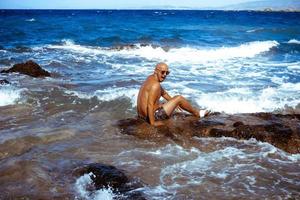 hombre guapo en la costa rocosa marina foto