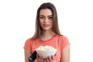 beautiful woman with a plate of pop corn and remote control looks into the camera and smiling photo