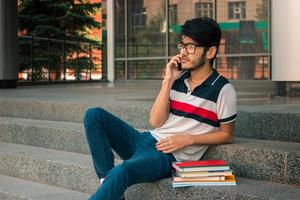 young handsome guy in glasses and books sitting on the stairs photo