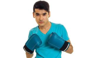 portrait of serious brunette sports man practicing box in blue gloves isolated on white background photo
