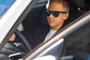 boy in glasses driving a car photo