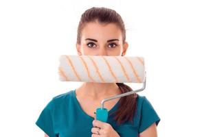 portrait of young beautiful brunette building woman in uniform with paint roller in hands makes renovation and looking at the camera isolated on white background photo