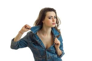 Portrait of a beautiful young brunette in jeans jacket that looks right and keeps hand collar photo