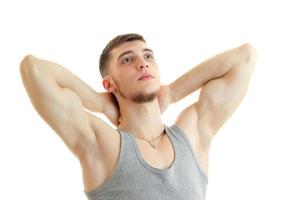 young strong guy with the session you muscles raised hands behind the neck and looking up isolated on a white background photo