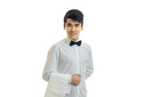 young waiter holds a towel on hand smiles and looks into a camera photo