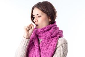 young girl in  warm scarf stands sideways and coughs isolated on white background photo