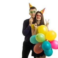 un chico y una chica sonrientes con conos en la cabeza sostenidos cerca de muñecos de papel y globos foto