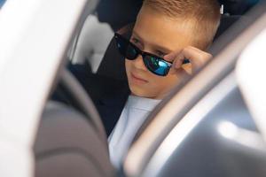 fashionable boy in sunglasses driving a car photo