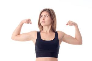 athletic girl in black top shows biceps on hand isolated  white background photo