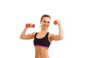 a young energetic girl in tank top and with dumbbells in your hands looks straight and smiling photo
