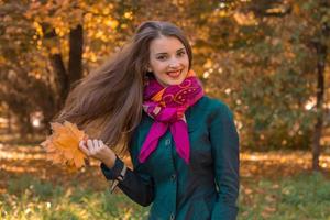 cheerful young girl keeps leaves and her hair fly through the air photo