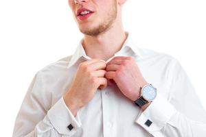 a young guy in a white shirt and with a clock on the arm straightens collar is isolated on a white background photo