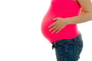 close up of pregnant brunette girl in big belly posing isolated on white background photo