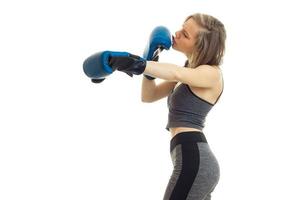 slender young fitness blonde standing in a gray sport suit and keeps hands in boxing gloves photo