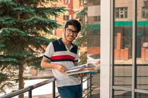 beautiful guy looks into the camera and holds in his hand book photo