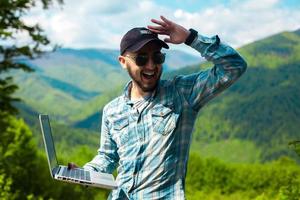 young man in sunglasses and with a laptop in hand photo