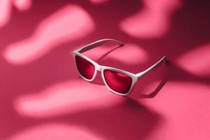 gafas de sol blancas sobre fondo magenta con escena de luz dura y espacio de copia. foto de estudio de gafas de sol modernas sobre fondo de tonos magenta viva.