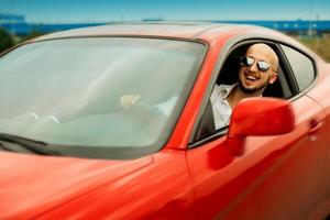 hombre feliz manejando un auto deportivo rojo foto