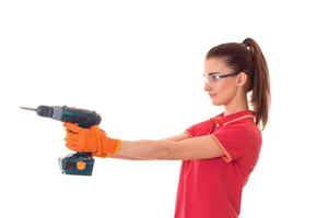 young charming builder girl in uniform with drill makes renovation isolated on white background photo